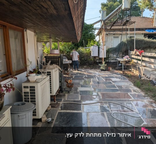 אדם עובד בחצר עם ציוד טכני ומיכלים